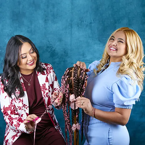 Beauty school instructor teaching hairstyling techniques to a cosmetology student