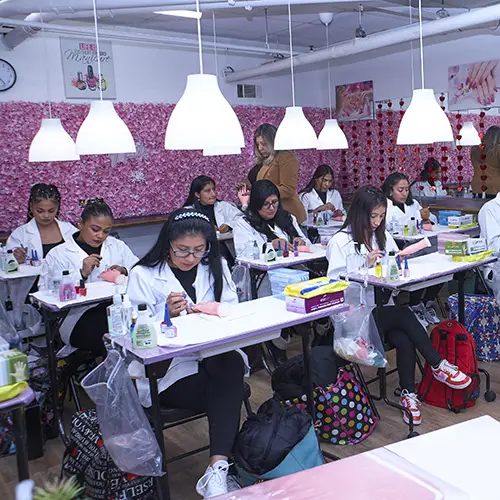 Nail technology students practicing manicure techniques during a beauty school class